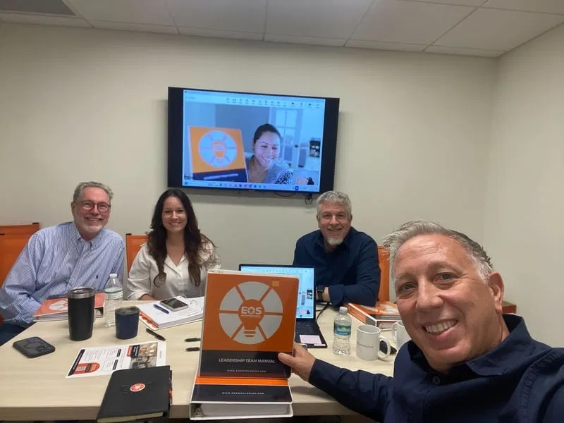 Leadership team working together around an EOS manual in a conference room